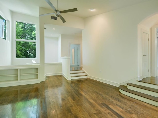 unfurnished living room featuring ceiling fan and dark wood-type flooring