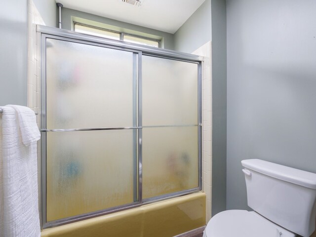 bathroom featuring shower / bath combination with glass door and toilet