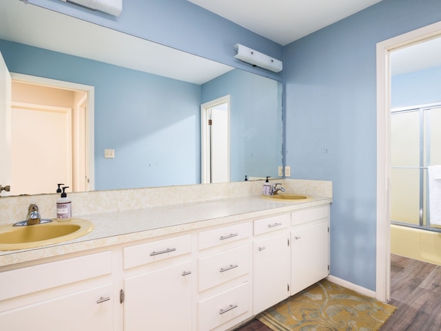 bathroom with hardwood / wood-style floors, vanity, and bath / shower combo with glass door