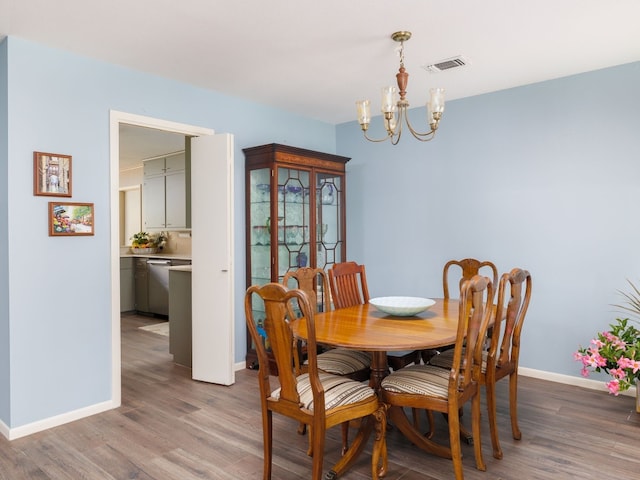 dining space with wood-type flooring and an inviting chandelier