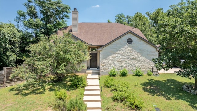 view of front of house with stone siding, a chimney, fence, and a front yard