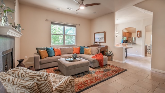 tiled living room featuring a tiled fireplace and ceiling fan