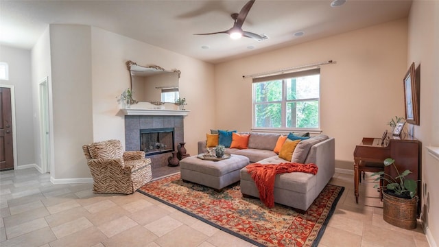 living room featuring ceiling fan, a fireplace, and baseboards