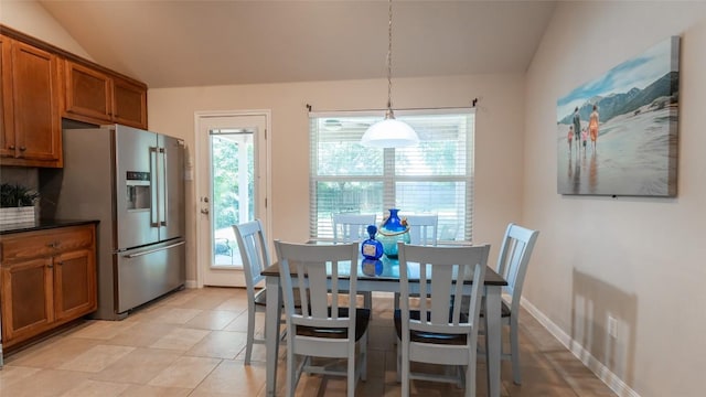 dining space featuring lofted ceiling, plenty of natural light, baseboards, and light tile patterned flooring