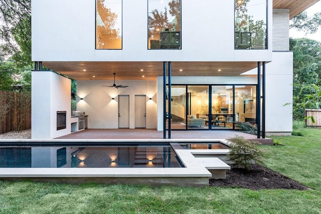 rear view of house featuring a fireplace, a patio, ceiling fan, and a lawn