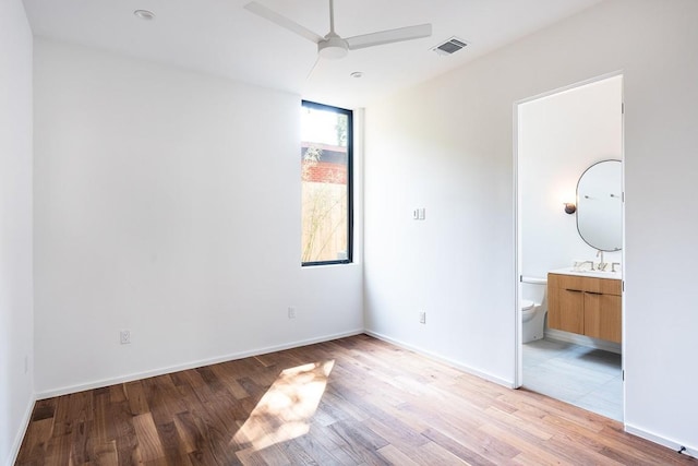 unfurnished bedroom featuring ensuite bathroom, light hardwood / wood-style flooring, ceiling fan, and sink