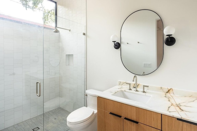 bathroom featuring vanity, toilet, and a shower with door