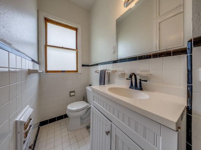 bathroom with tile patterned flooring, vanity, toilet, and tile walls