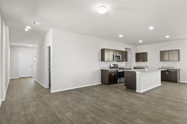 kitchen with dark hardwood / wood-style flooring, stainless steel appliances, an island with sink, sink, and dark brown cabinets