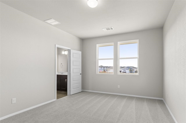 unfurnished bedroom with ensuite bathroom and light colored carpet