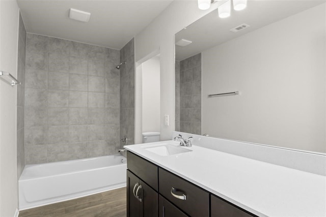 full bathroom featuring toilet, tiled shower / bath, and vanity