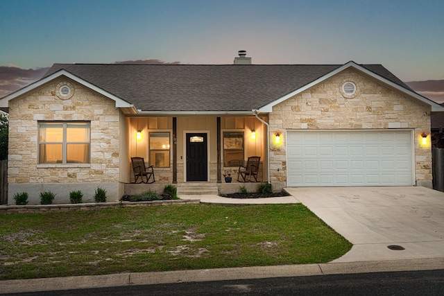 ranch-style house featuring a garage, covered porch, and a yard