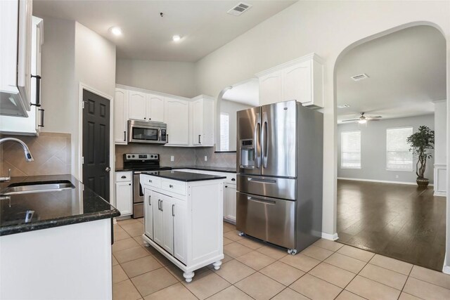 kitchen with appliances with stainless steel finishes, white cabinetry, a kitchen island, ceiling fan, and sink