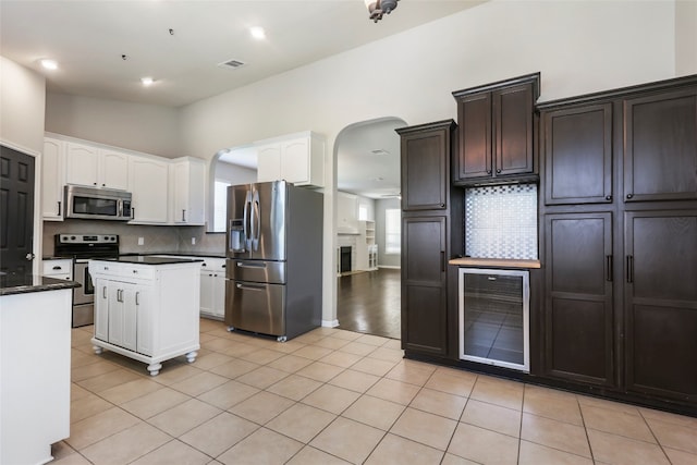 kitchen featuring light tile patterned floors, tasteful backsplash, beverage cooler, stainless steel appliances, and vaulted ceiling