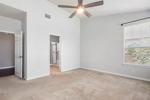 unfurnished bedroom featuring light carpet, connected bathroom, and ceiling fan