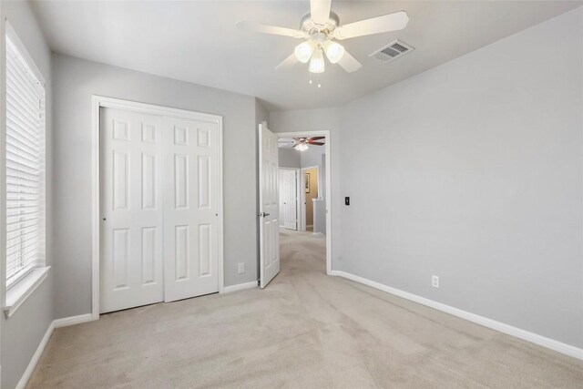 unfurnished bedroom with ceiling fan, light colored carpet, and a closet