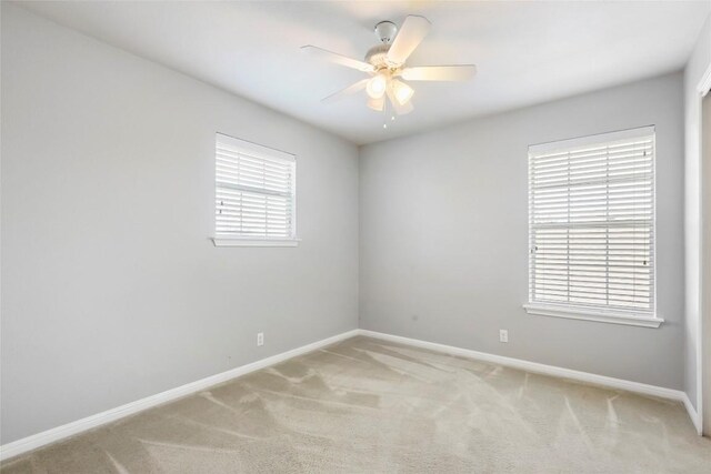 carpeted empty room with a healthy amount of sunlight and ceiling fan