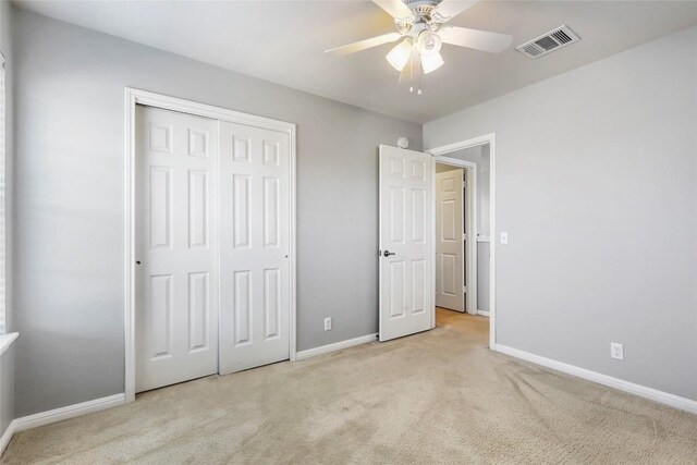 unfurnished bedroom featuring light carpet, ceiling fan, and a closet