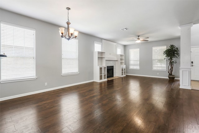 unfurnished living room with ceiling fan with notable chandelier, a fireplace, and dark hardwood / wood-style flooring