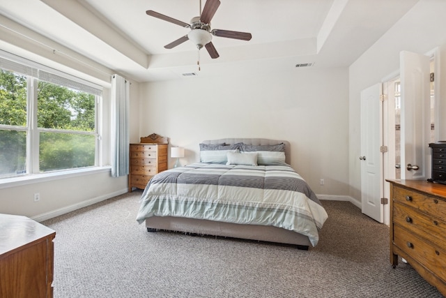 bedroom with ceiling fan, carpet flooring, and a raised ceiling