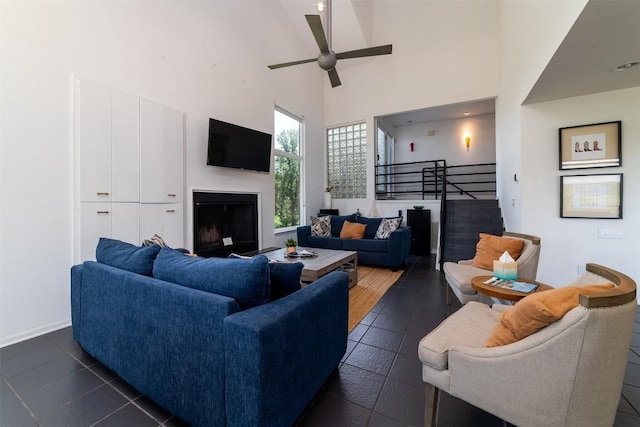 living room featuring a towering ceiling, dark tile patterned flooring, and ceiling fan