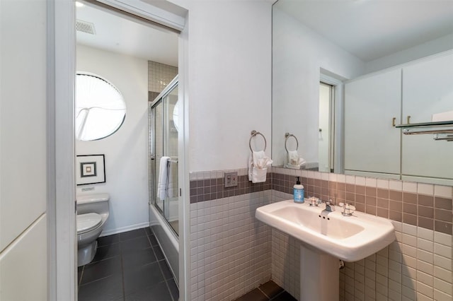 full bathroom with tile patterned floors, sink, toilet, enclosed tub / shower combo, and tile walls