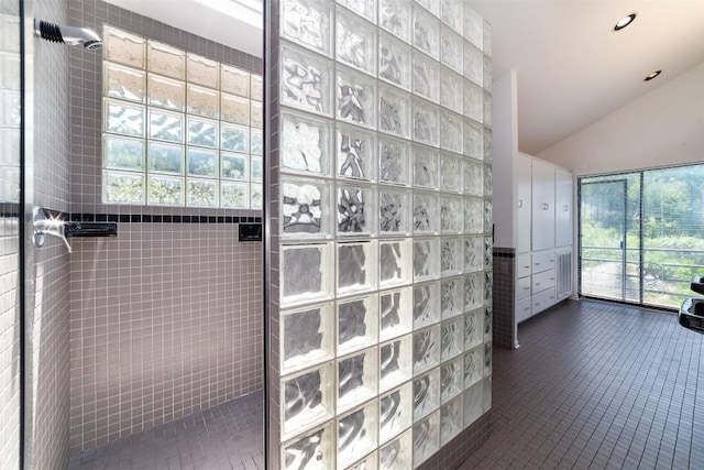 bathroom featuring tiled shower, tile patterned floors, a wealth of natural light, and tile walls