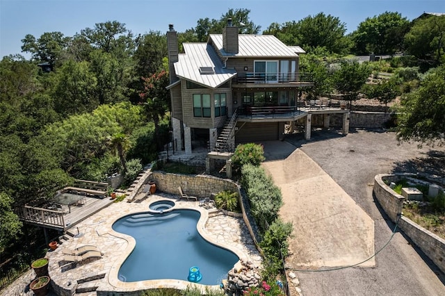 rear view of house with a pool with hot tub, a patio area, and a balcony