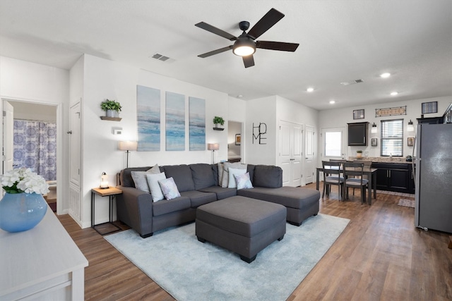 living room with dark hardwood / wood-style flooring and ceiling fan