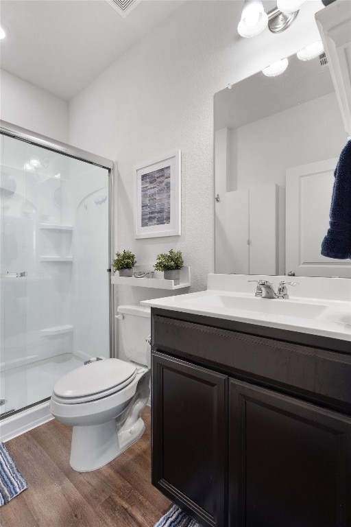 bathroom with toilet, vanity, a shower with shower door, and hardwood / wood-style flooring