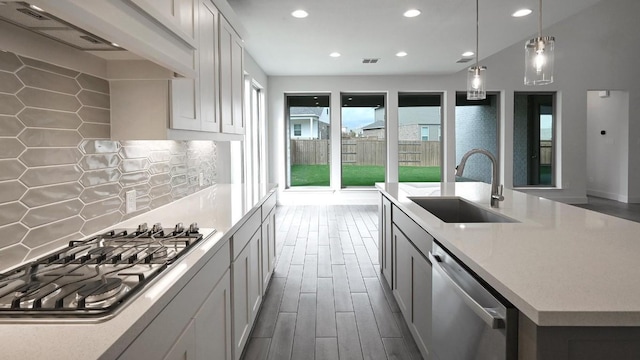 kitchen with a center island with sink, sink, appliances with stainless steel finishes, decorative light fixtures, and white cabinetry