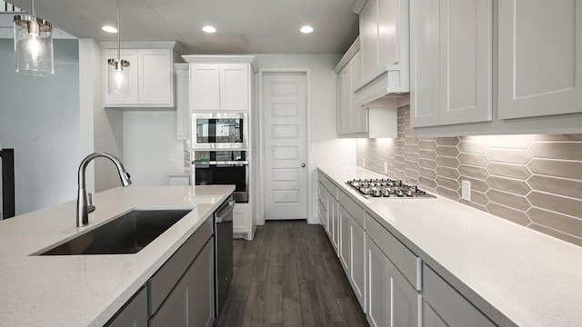 kitchen featuring pendant lighting, backsplash, white cabinets, sink, and stainless steel appliances