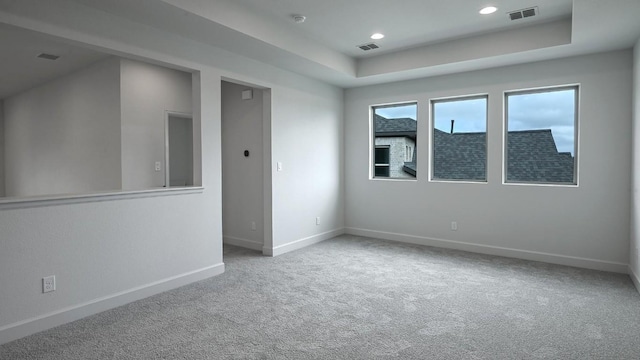 empty room featuring carpet flooring and a raised ceiling