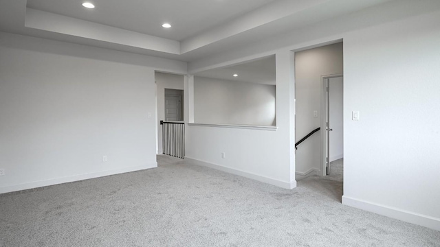 carpeted empty room featuring a tray ceiling