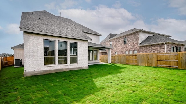 rear view of property featuring central AC unit, a yard, and a patio