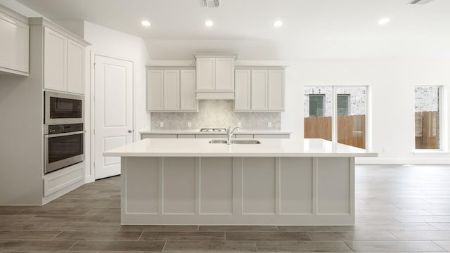 kitchen featuring appliances with stainless steel finishes, sink, white cabinetry, and an island with sink