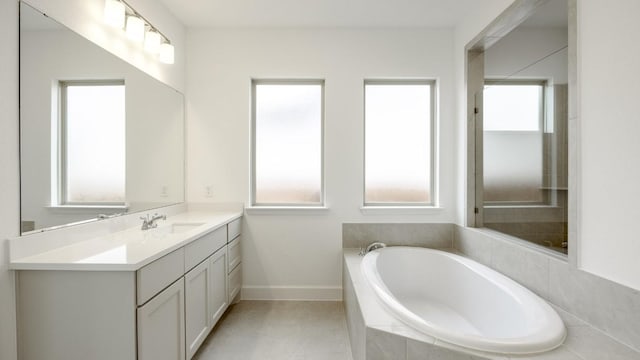 bathroom with tile patterned flooring, vanity, and a relaxing tiled tub