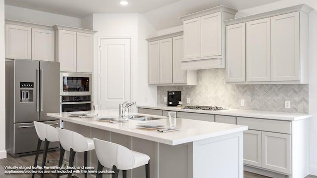 kitchen featuring a breakfast bar area, sink, an island with sink, and stainless steel appliances