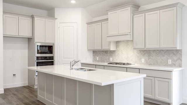 kitchen featuring decorative backsplash, an island with sink, stainless steel appliances, and sink