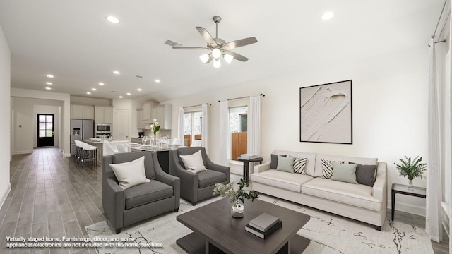 living room with ceiling fan and light wood-type flooring