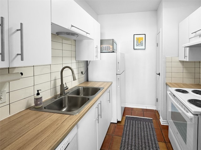 kitchen with sink, tasteful backsplash, dark tile patterned floors, white appliances, and white cabinets