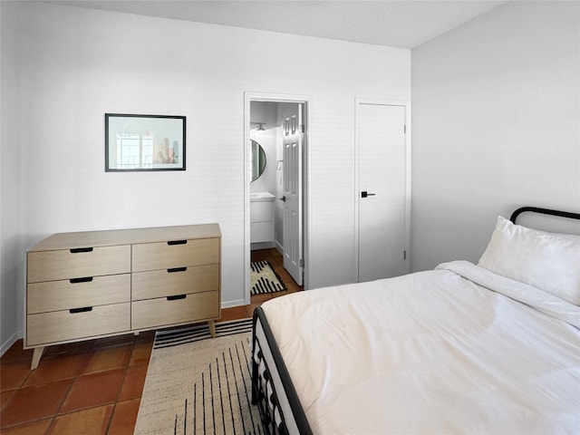 bedroom with ensuite bathroom and dark tile patterned floors