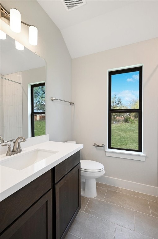 bathroom featuring a wealth of natural light, toilet, tile floors, vanity, and lofted ceiling