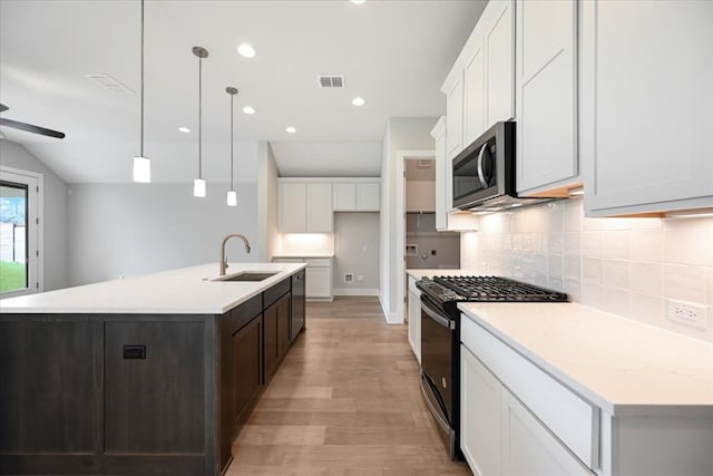 kitchen with sink, light hardwood / wood-style floors, black range with gas stovetop, and a center island with sink