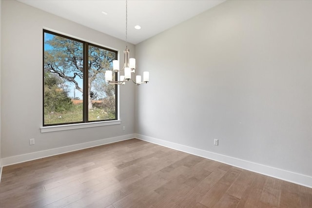 empty room featuring a notable chandelier and hardwood / wood-style floors