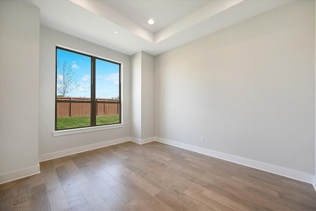 spare room with a tray ceiling and hardwood / wood-style floors