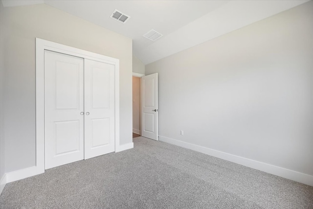 unfurnished bedroom featuring vaulted ceiling, carpet, and a closet