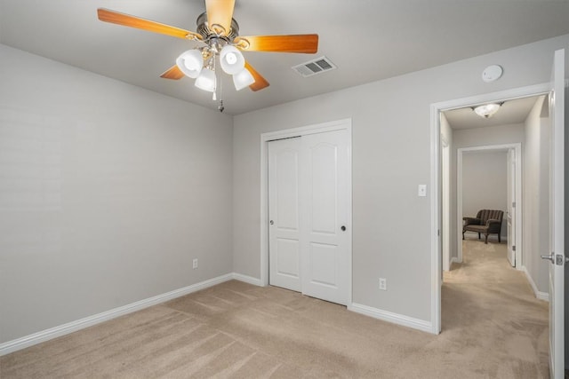 unfurnished bedroom featuring ceiling fan, a closet, and light colored carpet