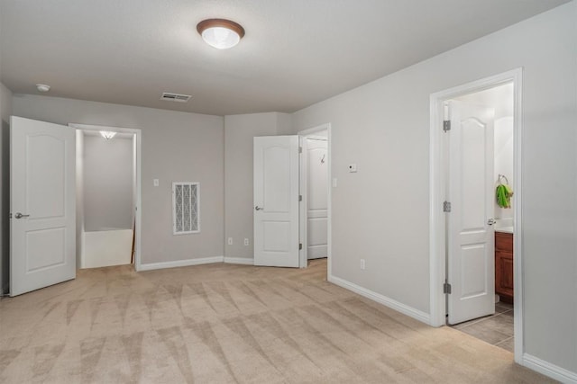 unfurnished bedroom featuring light colored carpet and connected bathroom