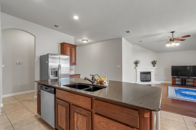 kitchen with a center island with sink, light tile patterned floors, sink, and appliances with stainless steel finishes